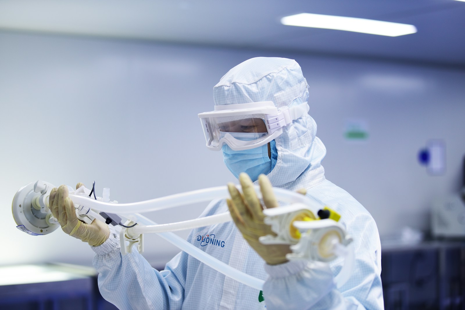 A person in a protective suit holding a device
